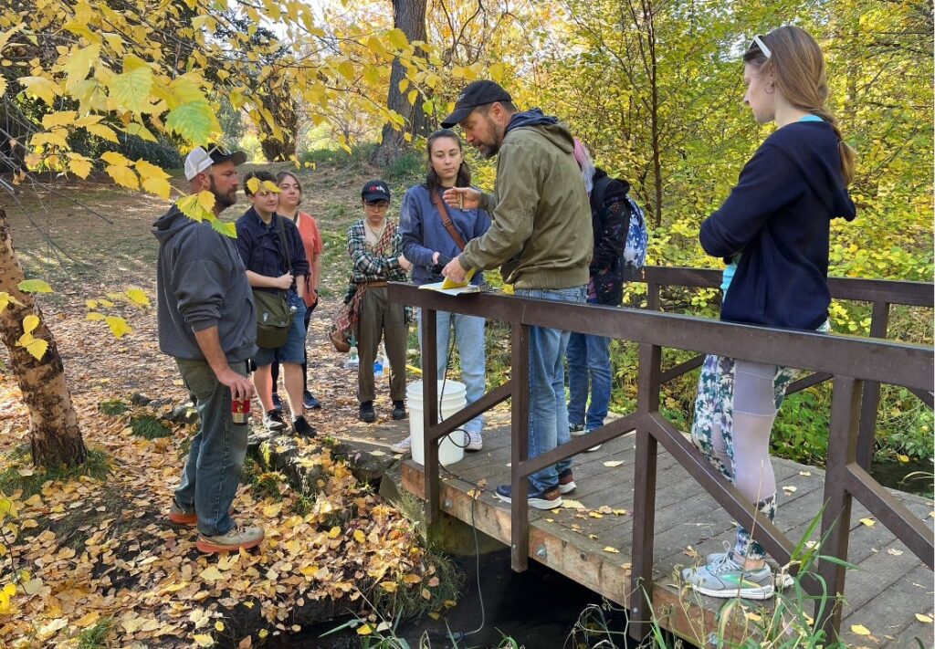 EWU geologist Chad Pritchard (on bridge) with students sampling Garden Springs creek in Spokane’s Finch Arboretum in autumn of 2024. The creek is fed with spring water originating near the Spokane International Airport. The sampling revealed levels of PFAS (Per-and Polyfluoroalkyl) chemicals in the creek well in excess of federal drinking water standards
